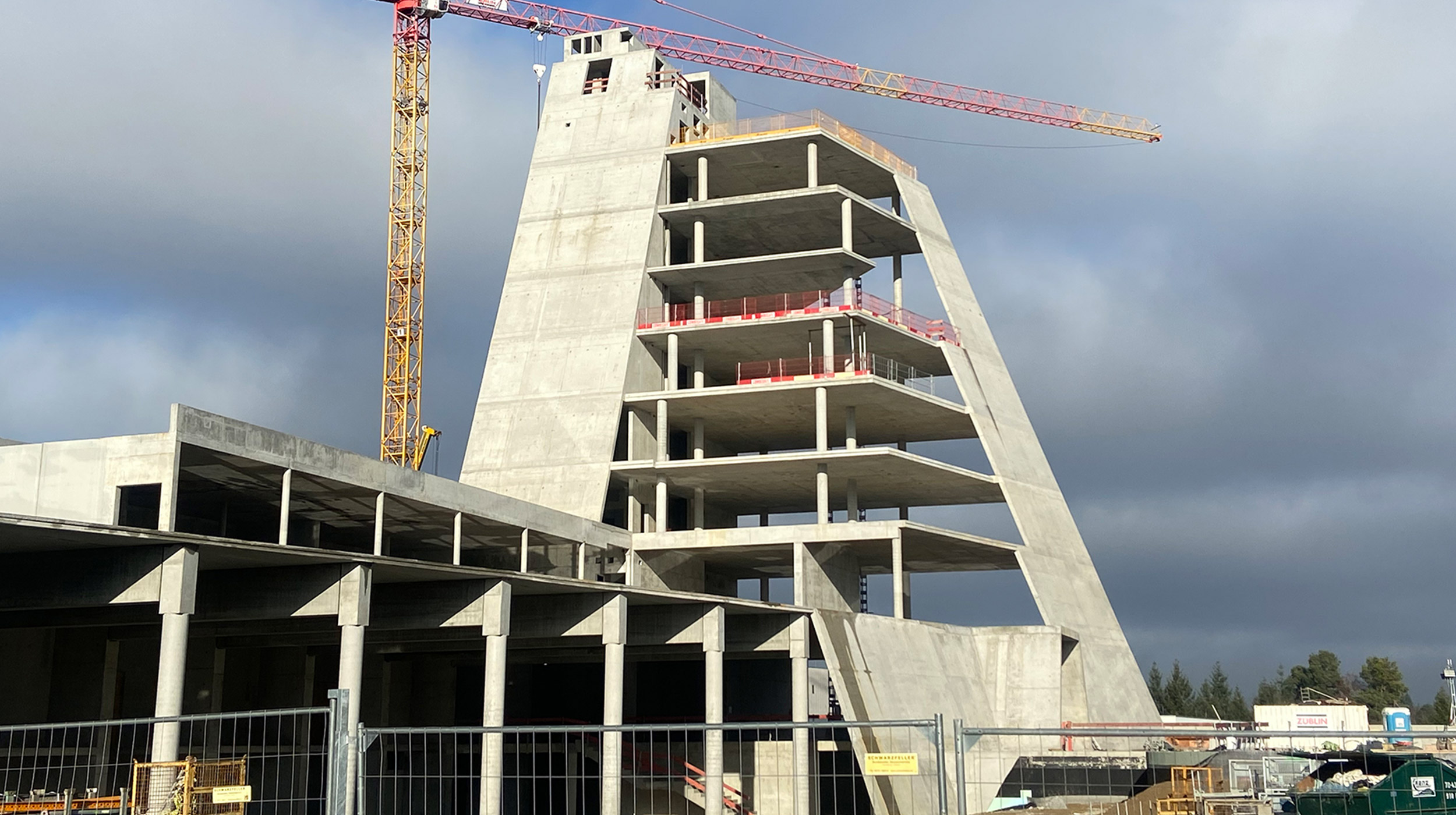 Für das neue Dynamikzentrum von Häfele in Nagold haben wir den Rohbau in Rekordzeit realisiert. Der multifunktionale Gebäudekomplex vereint moderne Logistik, Ausstellungsflächen und Gemeinschaftsbereiche – und überzeugt durch seine außergewöhnliche Architektur. Besonders markant ist der rund 50 Meter hohe Turm mit geneigten Außenwänden im Neigungswinkel von 70 Grad.